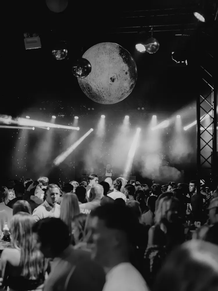 Publiek in zwart-wit onder de lichtshow op Alfa Open Air