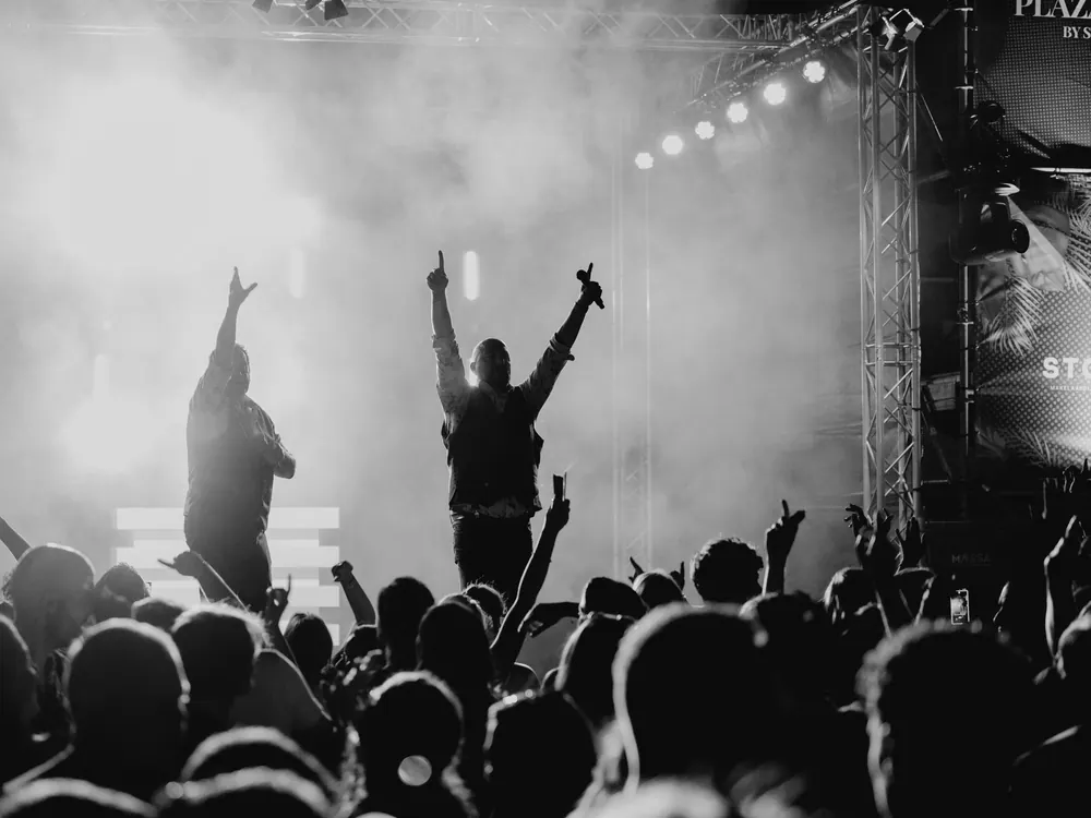 Silhouetten van juichend publiek in de rook, in zwart-wit