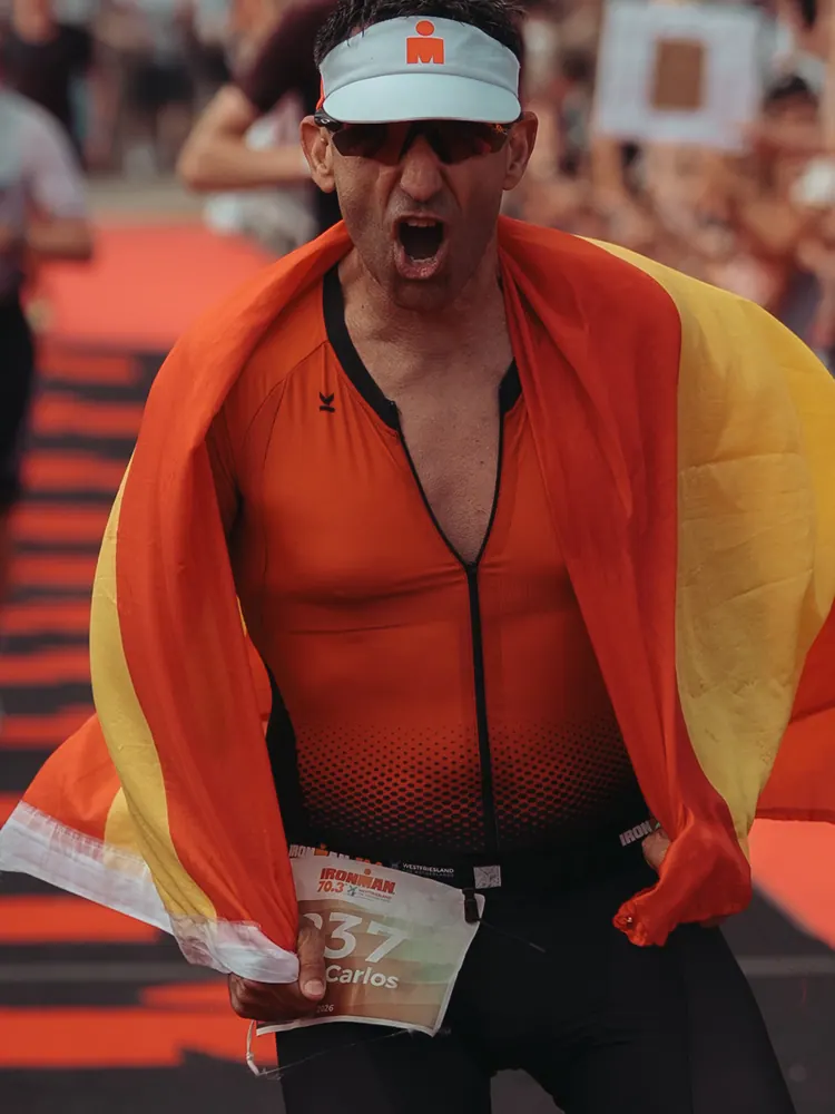 Triatleet met een Belgische vlag om zijn schouders na de finish