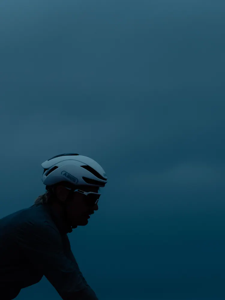 Silhouet van een wielrenner tegen een donkerblauwe lucht