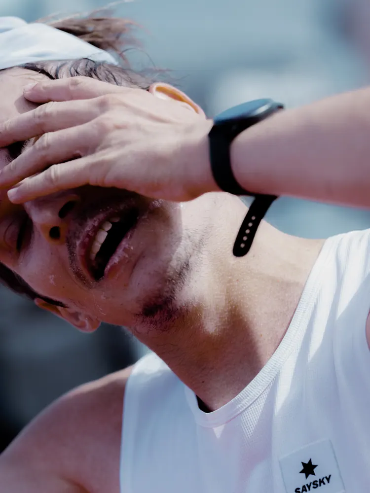Uitgeputte hardloper houdt zijn hand op zijn hoofd na de finish