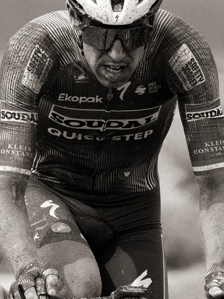 Renner van Soudal Quick-Step met modder op zijn gezicht, in zwart-wit
