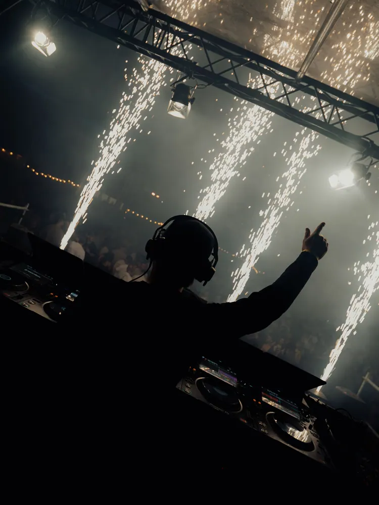 DJ achter de draaitafel tussen vuurwerkfonteinen op LYVES