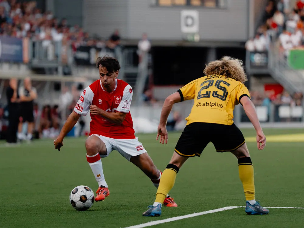 Duel tussen MVV en Roda JC om de bal, de tribune vol op de achtergrond