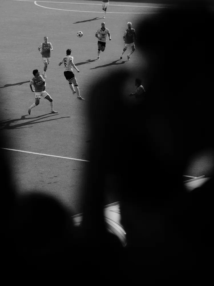 Spelers op het veld gezien langs een silhouet op de tribune