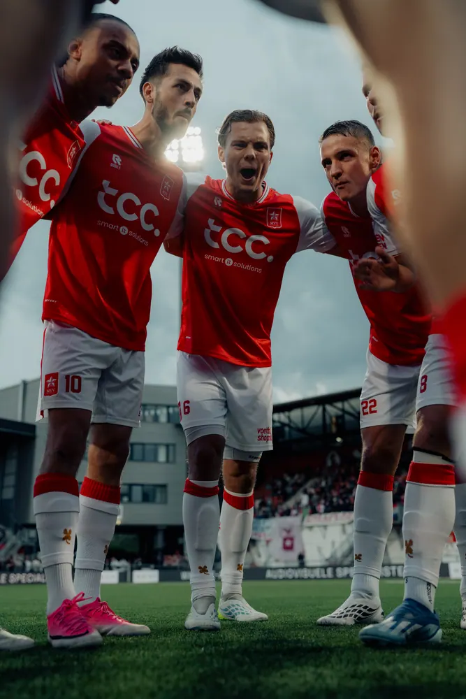 MVV-spelers in een kring voor de aftrap, gefotografeerd van onderaf