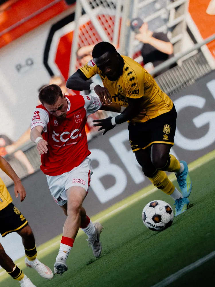 Duel tussen MVV en Roda JC om de bal voor een reclamebord
