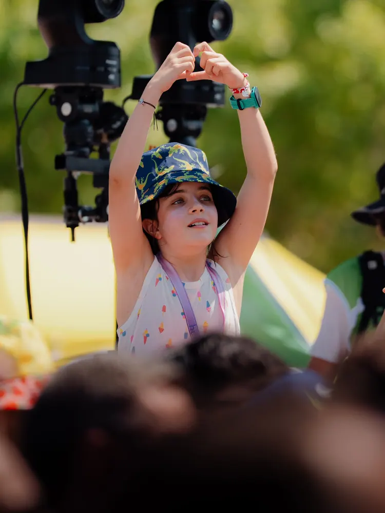 Meisje maakt een hartje met haar handen tussen de tv-camera's