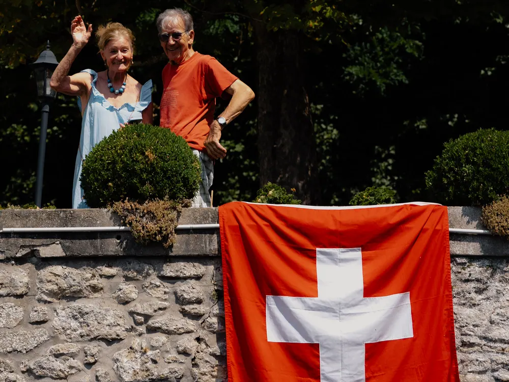 Supporters zwaaien boven een Zwitserse vlag langs het parcours