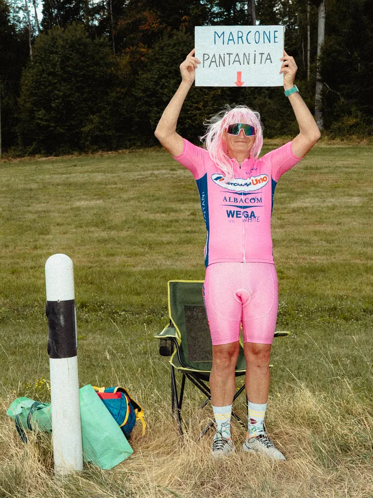 Fan in roze wielertenue houdt een bord omhoog in het gras