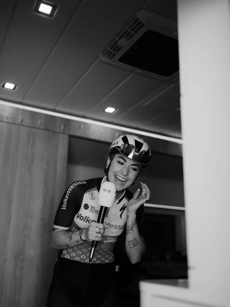 Renster van VolkerWessels lacht tijdens een interview met de NOS in de teambus, in zwart-wit